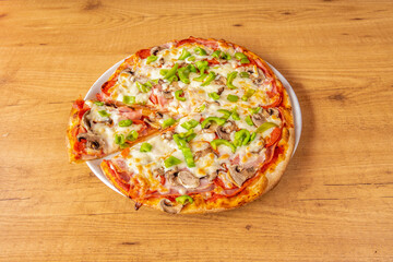 Pizza with ham, mushrooms, tomato and melted cheese, green peppers and wheat flour