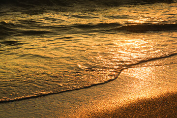Waves and sand texture on the beach at sunset