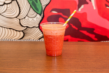 Strawberry juice slush in a plastic cup and yellow straw