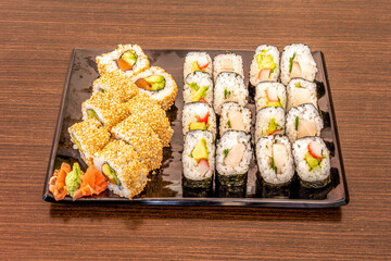 Assorted sushi tray with uramaki dragon roll stuffed with avocado, Norwegian salmon and nori seaweed. Maki stuffed with butterfish, Japanese rice, surimi and ripe avocado
