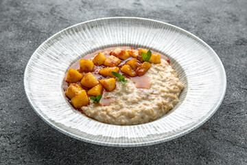 Oatmeal in milk with caramelized peach. Ready menu for the restaurant. Neutral gray blue textured background