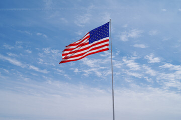Large American flag shown against a blue sky with some clouds in Arizona.