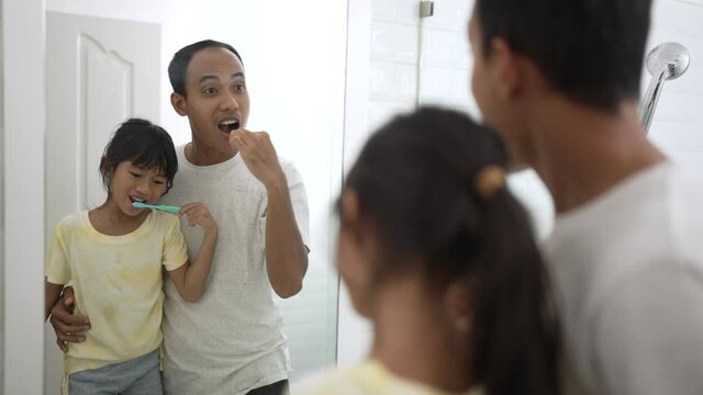 kid learn how to brush teeth with dad