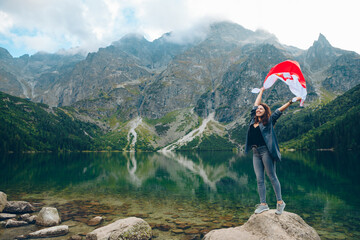 young pretty woman with poland flag in mountains near lake