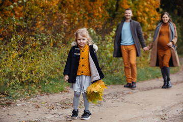 Fototapeta premium father daughter and pregnant mother walking by autumn park