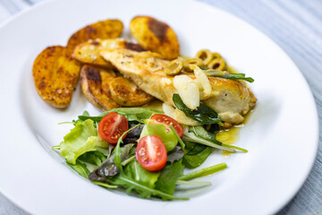 chicken breast baked on sage with green olive sauce with salad and potatoes
