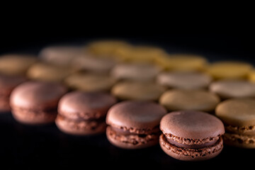 chocolate, coffee, vanilla, lemon and strawberry macaroons on black background