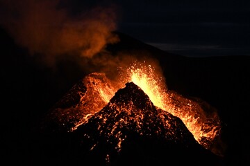 Eruption at Fagradalsfjall, Iceland. Red and orange incandescent lava is erupted from the volcanic vent. Taken at night, the lava is isolated on a black background.