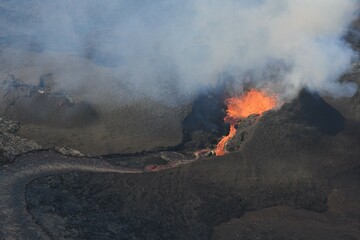 Erupting vent and lava flow at Fagradalsfjall, Iceland. The lava field is black, with red and...