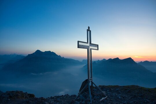 beautiful Stunning sunset with cross on top of mountain peak Switzerland