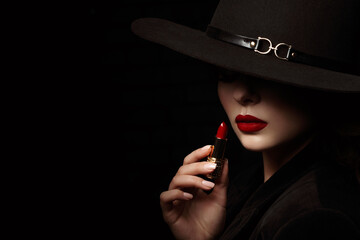 Beauty portrait of elegant woman with luxury lips makeup holding red lipstick. Model hides her face...