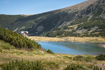 Vivid, blue, glacial lake and a mountain hut on Rila mountain, on the track to Musala summit, under a clear, blue sky