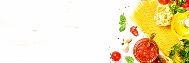 Italian food background. Pasta, tomato sauce, herbs and spices at white kitchen table. Long banner format.