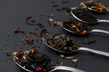 An assortment of dry tea in teaspoons, on a dark background. Red, fruit, green, black and herbal...