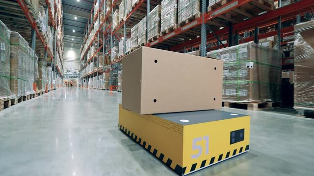 Robotic transporter is relocating a box in the warehouse