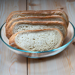 slices of white wheat bread in a glass bowl on a light wooden surface