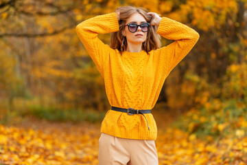 Fashion portrait of a beautiful woman with stylish sunglasses in a vintage knitted yellow sweater...