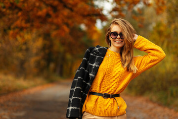 Stylish beautiful young cheerful girl with a smile and glasses in a fashionable bright yellow...