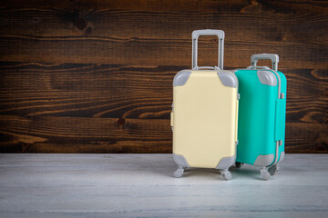 Miniature travel suitcases on a light and dark wooden background