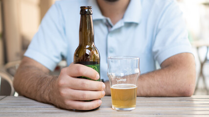 Single man with a beer bottle. Man holding a beer. Man holding lagger beer