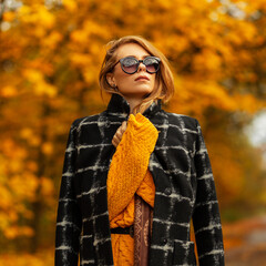 Pretty stylish woman with Caucasian face in stylish black coat and yellow knitted sweater walks...