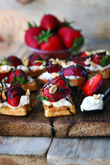 French waffles with strawberries and chocolate, cream cheese and nuts.