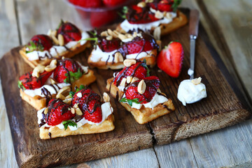French waffles with strawberries and chocolate, cream cheese and nuts.