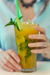 Woman holds delicious handmade lemonade with lime.