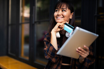 Urban happy woman using digital tablet. Beautiful young woman buying online