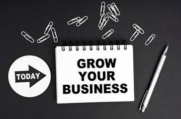 On a black background, a round plate - Today and a notebook with the inscription - GROW YOUR BUSINESS
