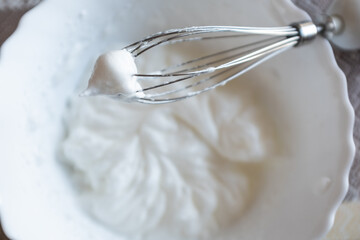 Whipped egg whites on mixer whisk. Process of cooking meringue. Baking dessert concept. Whipped egg whites - beaten italian meringue on a whisk