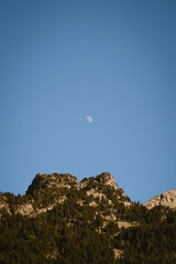 Crescent moon over the summit of a mountain on a sunny summer evening