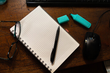 workspace with glasses, pen, mouse and notebook on brown desk