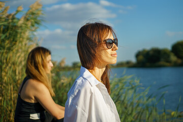 Happy millennial women friend enjoying activities in nature and looking at rural landscape with river