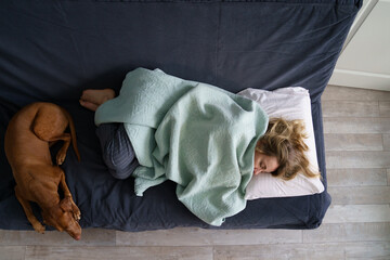 Tired woman sleep on couch near calm comforting dog, view from above. Single or divorced female...