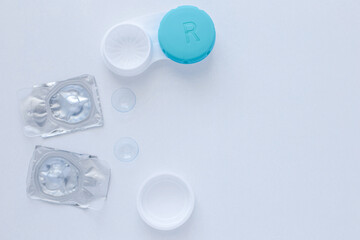 A container for lenses, two sealed lenses and lenses lying on a table on the side on a white background with a place for text. top view, flat lay, copy space, isolate
