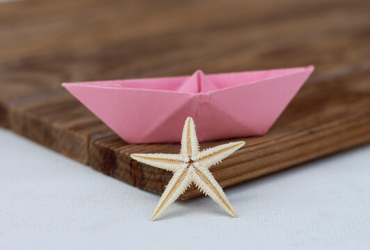  Estrella de mar y un barco de papel sobre una superficie de madera