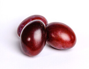 three plums on a white background