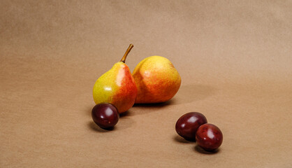 assorted fruits, two pears and plums on craft paper