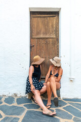 Girlfriends in summer enjoying the holidays. Caucasian girls sitting by a door enjoying the heat on vacation