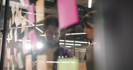Creative multiethnic team of developers brainstorming ideas, putting stickers on glass board. Students working on project 4k footage