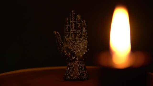 Fortune teller hand or palmistry on the witch table. Palmistry with black palm and candle. Magic alchemy spirituality symbol. Palm reading in mystic and occult environment.