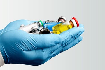 The doctor's hand holds a bottle with a coronavirus vaccine on a background.