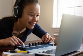 A woman making digital music and editing photos on computer. Work at home.