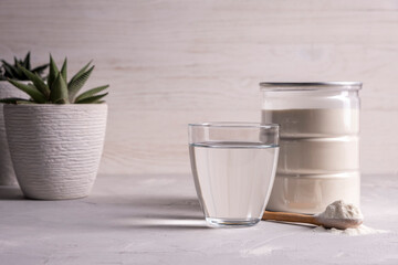 Collagen powder with a glass of water on a gray background with copy space.