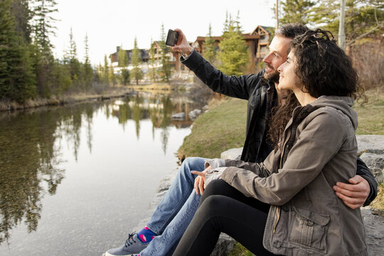Couple taking selfie on river bank in resort