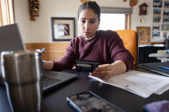 Focused female farmer with credit card working at laptop in office