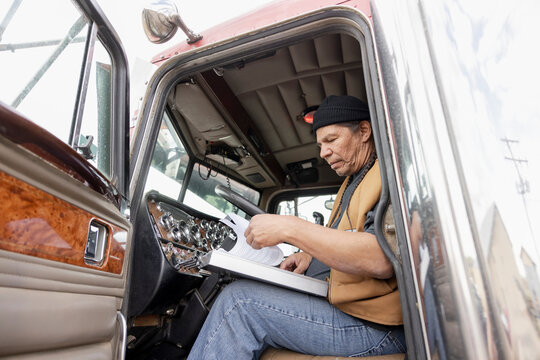 Male farmer with paperwork in cabin of semi truck