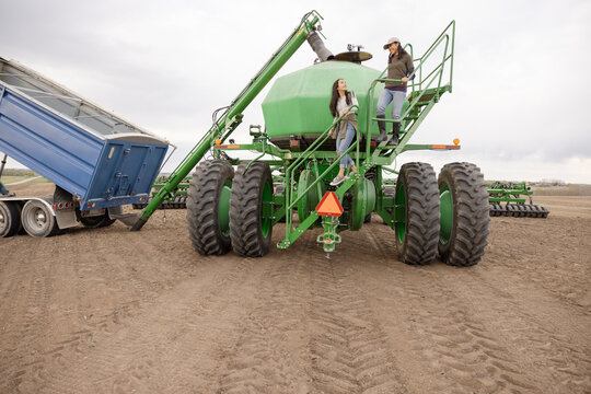 Mother And Daughter Farmers On Farming Equipment Steps On Farm