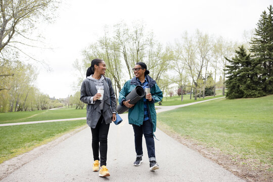 Cheerful Women Carrying Yoga Mats Walking In Park